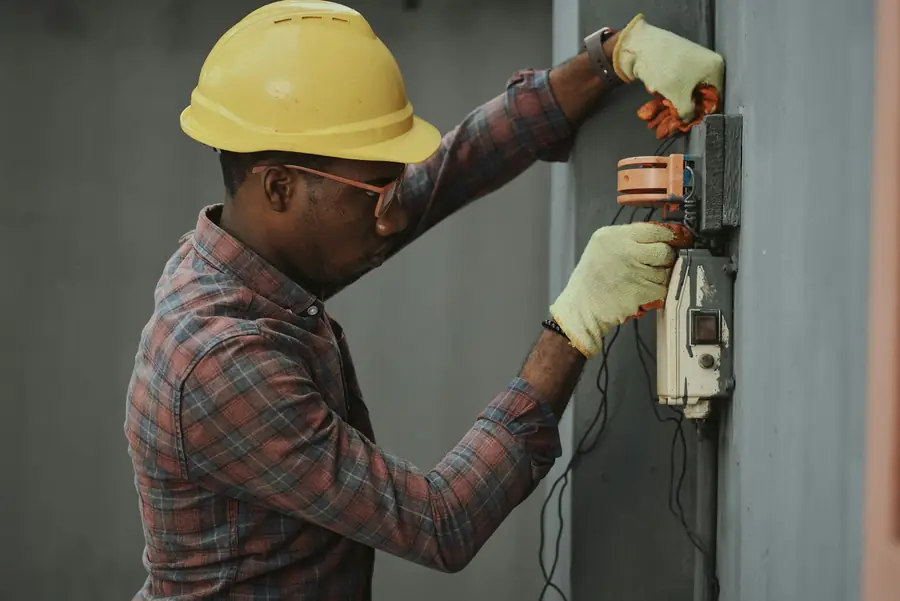 Electrician in a hard hat testing an exterior electrical meter
